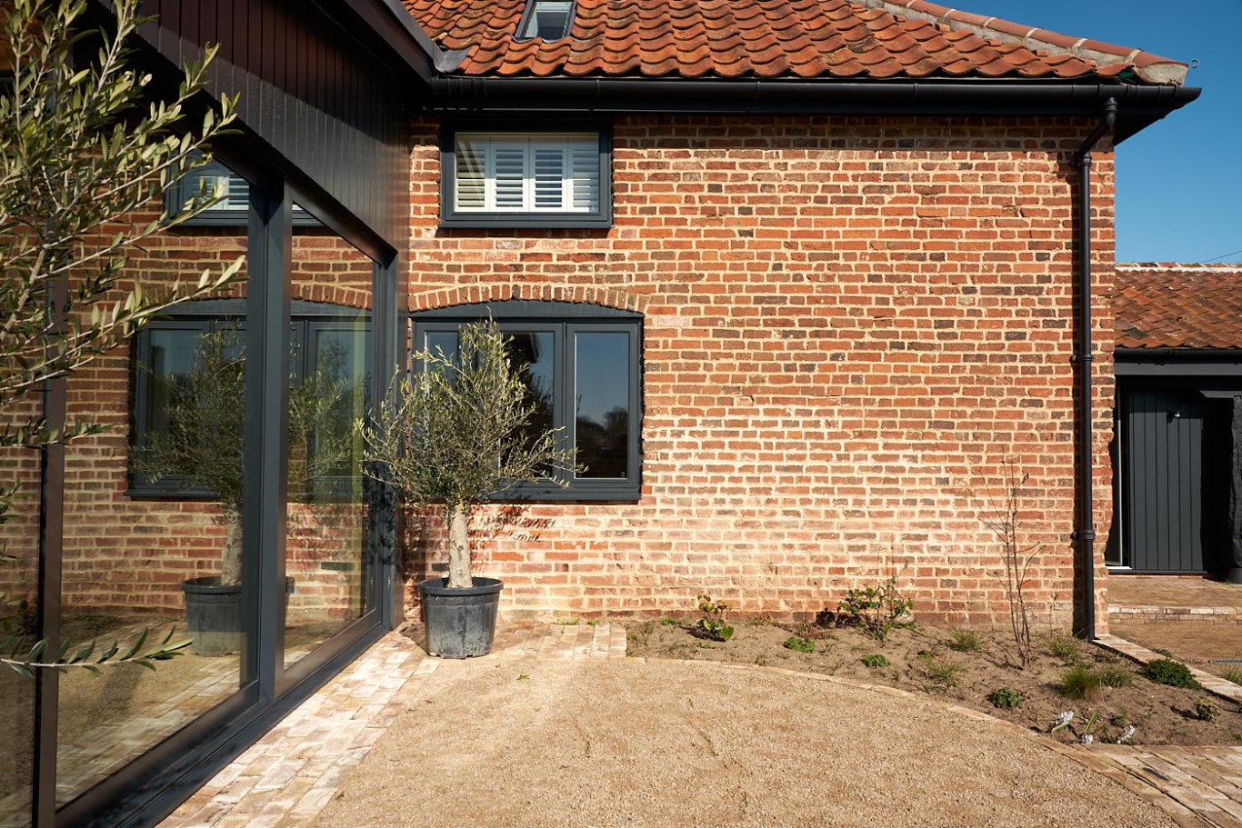 Red brick barn with red pantiles roof updated with modern double-glazed aluminium windows.